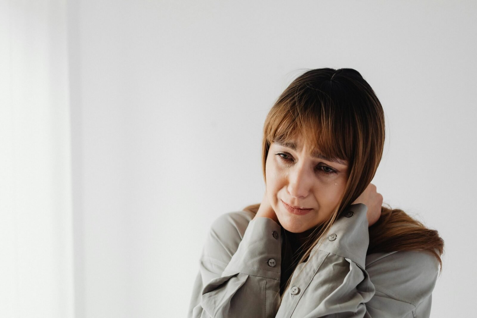 A thoughtful woman expressing deep emotion against a white background.